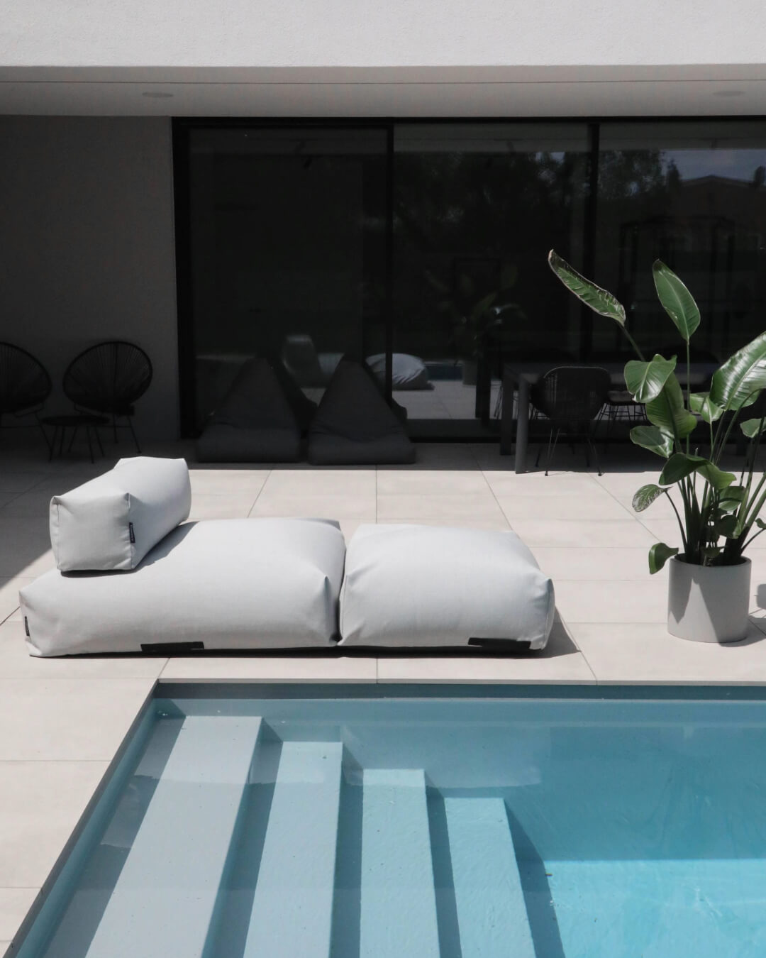 Ein Poolsofa Double in Grau steht am Rand des Pools auf der Terrasse. 