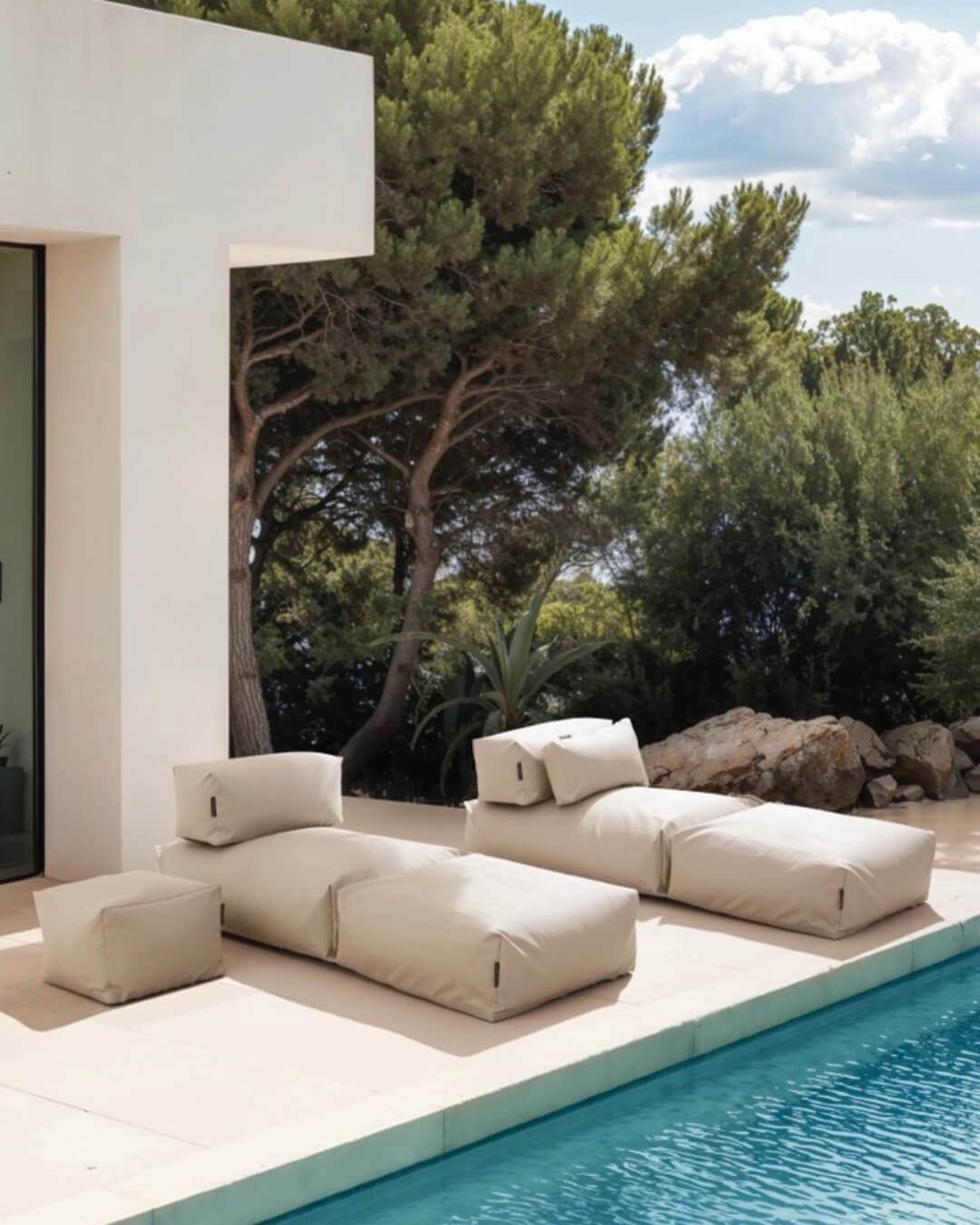 Zwei Poolsofas Singel stehen nebeneinander neben dem Pool. Ein Pouf in small und ein Relaxkissen wurde dazu dekoriert. $ Poolsofa Single | Perlmutt